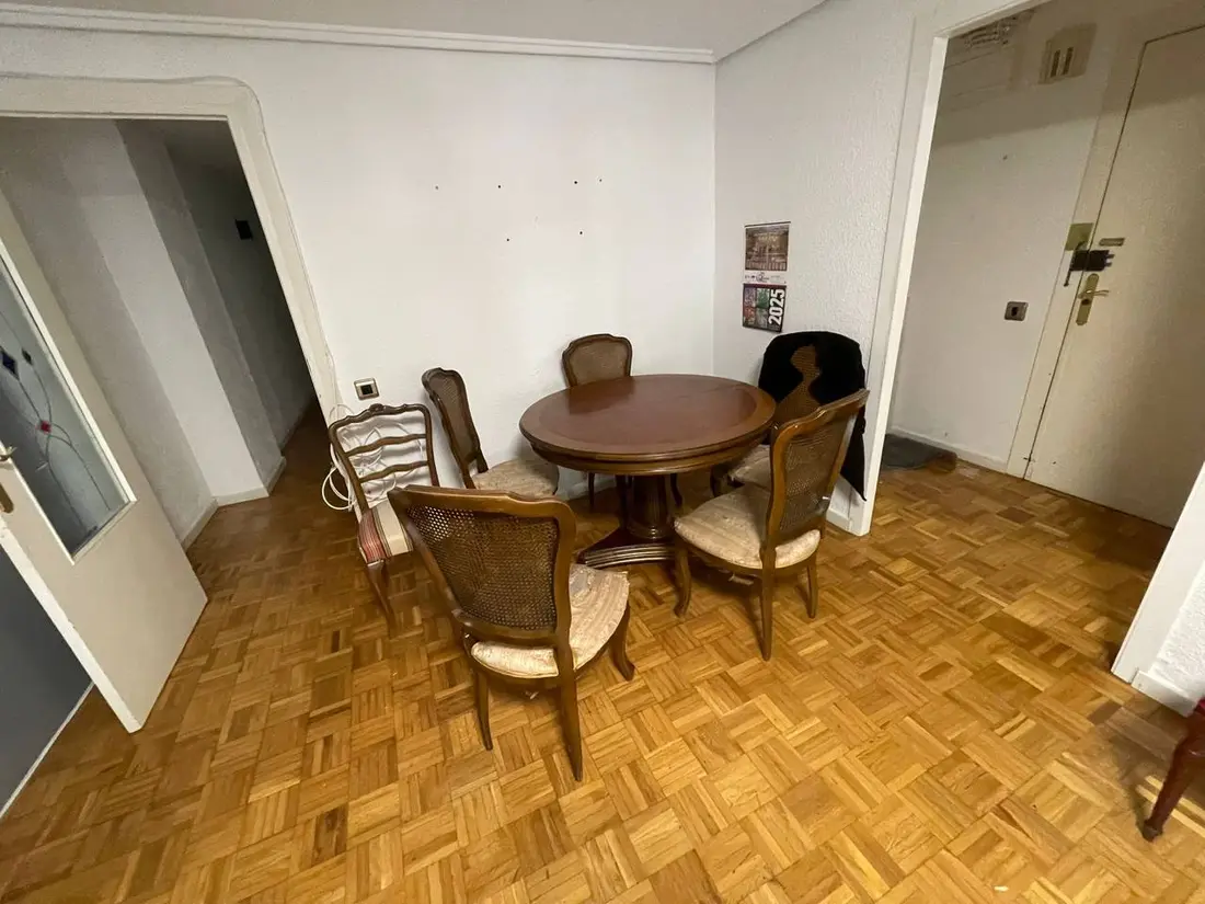 Comedor con mesa y sillas clásicas en un vaciado de piso heredado en Valencia